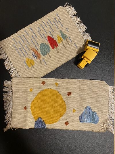 Two woven placemats — one showing rain, one showing sun