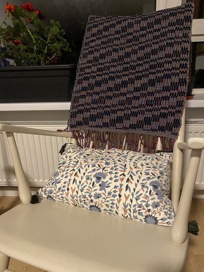 Navy and terracotta lap throw draped over a rocking chair